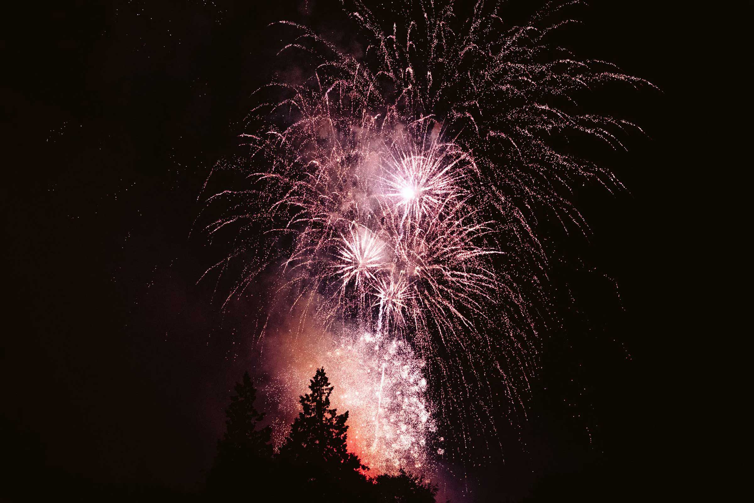 Wedding pyromusical display illuminating the night sky above a country house venue